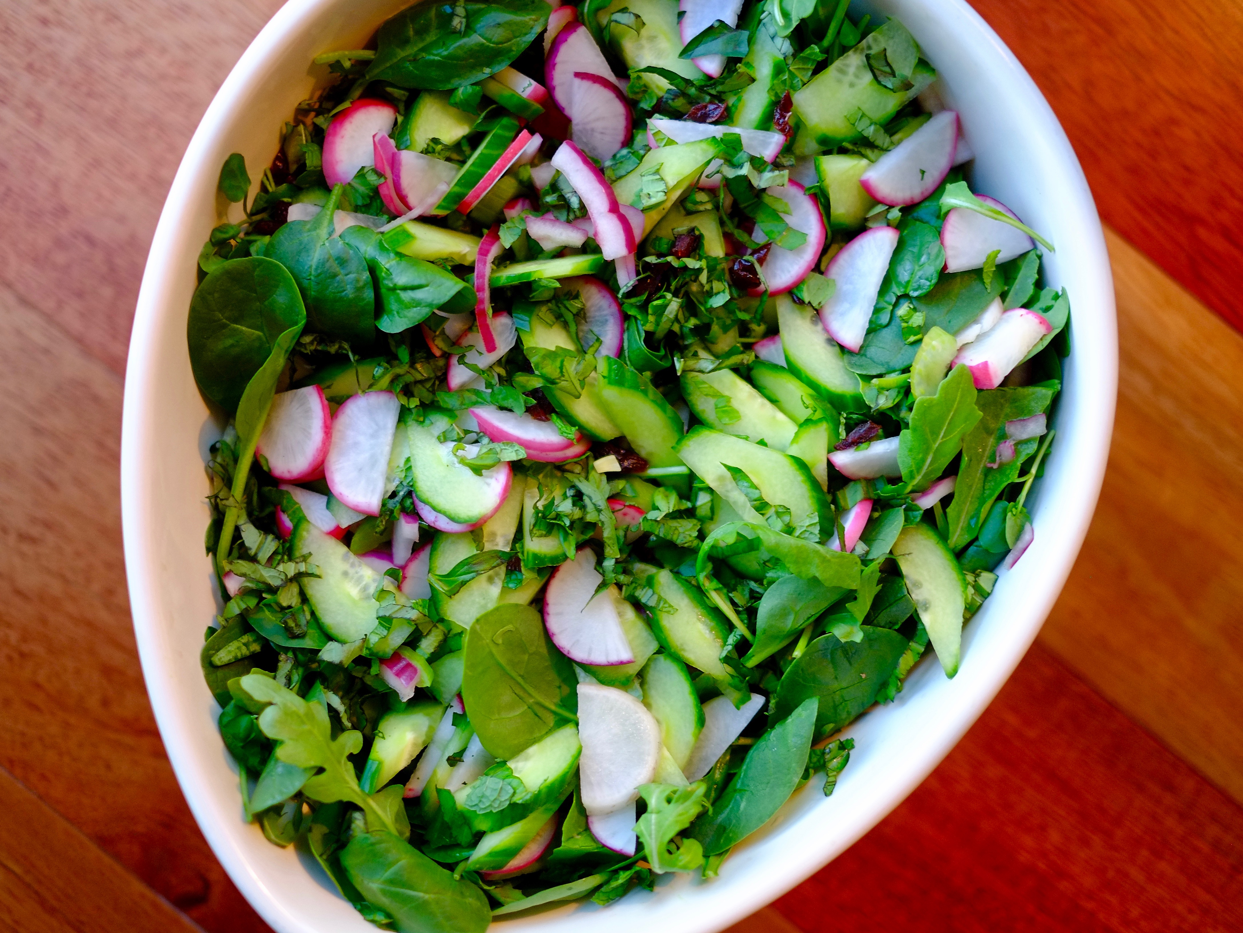 Big oval bowl full of green salad and radishes.