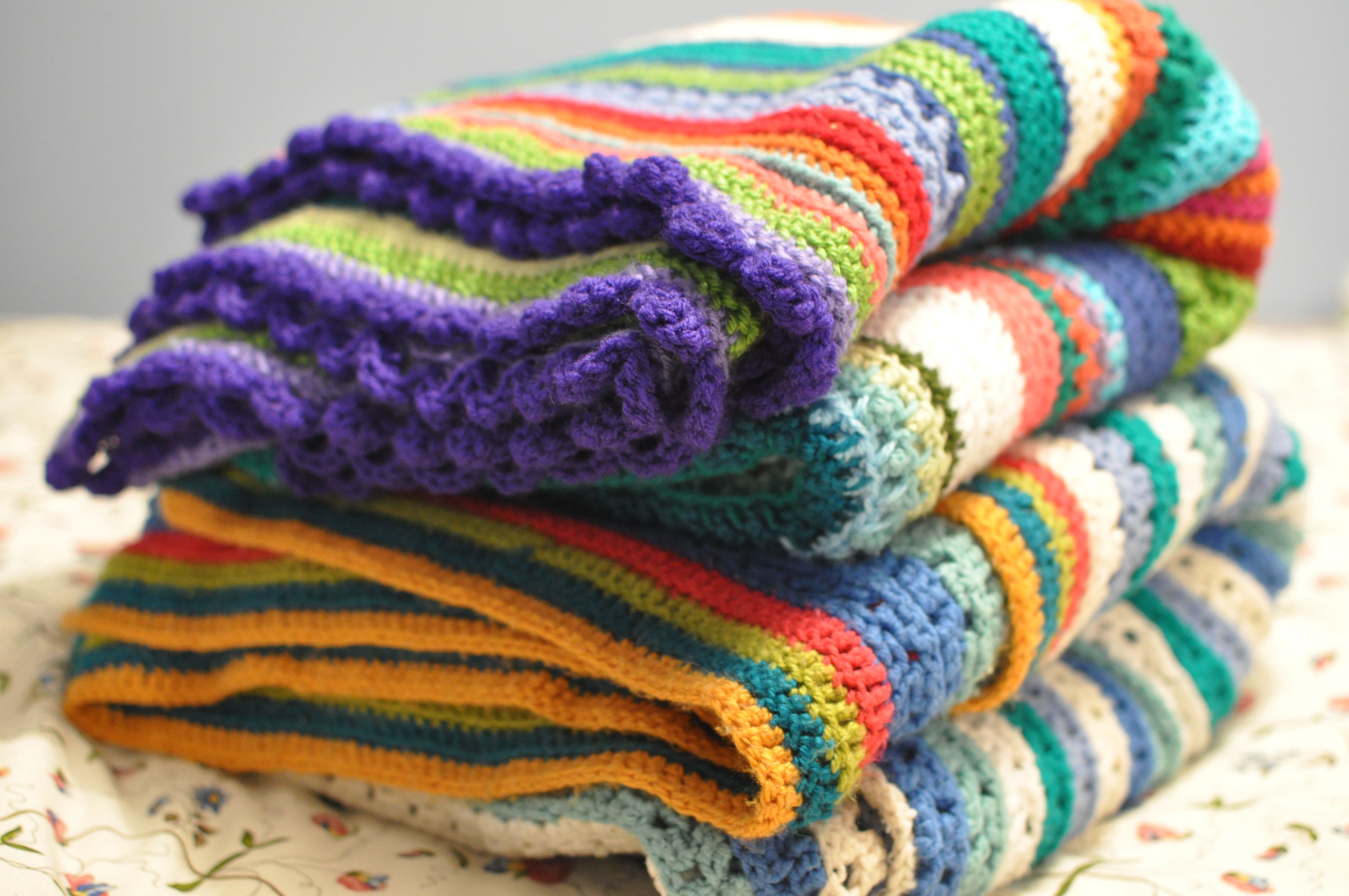 Stack of colourful crochet blankets.