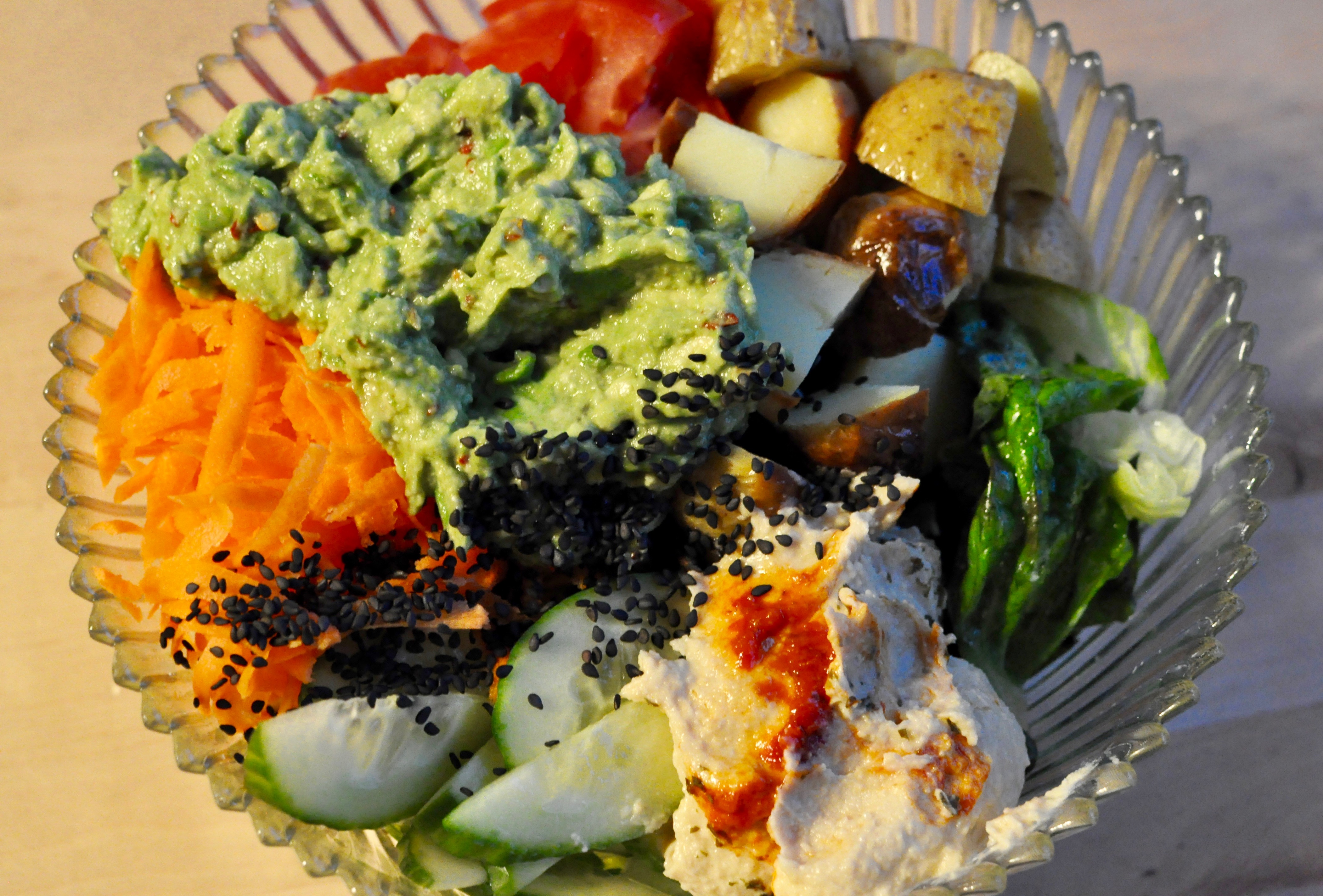 Salad with avocado, potato, shredded carrots, cucumbers, and tomato.
