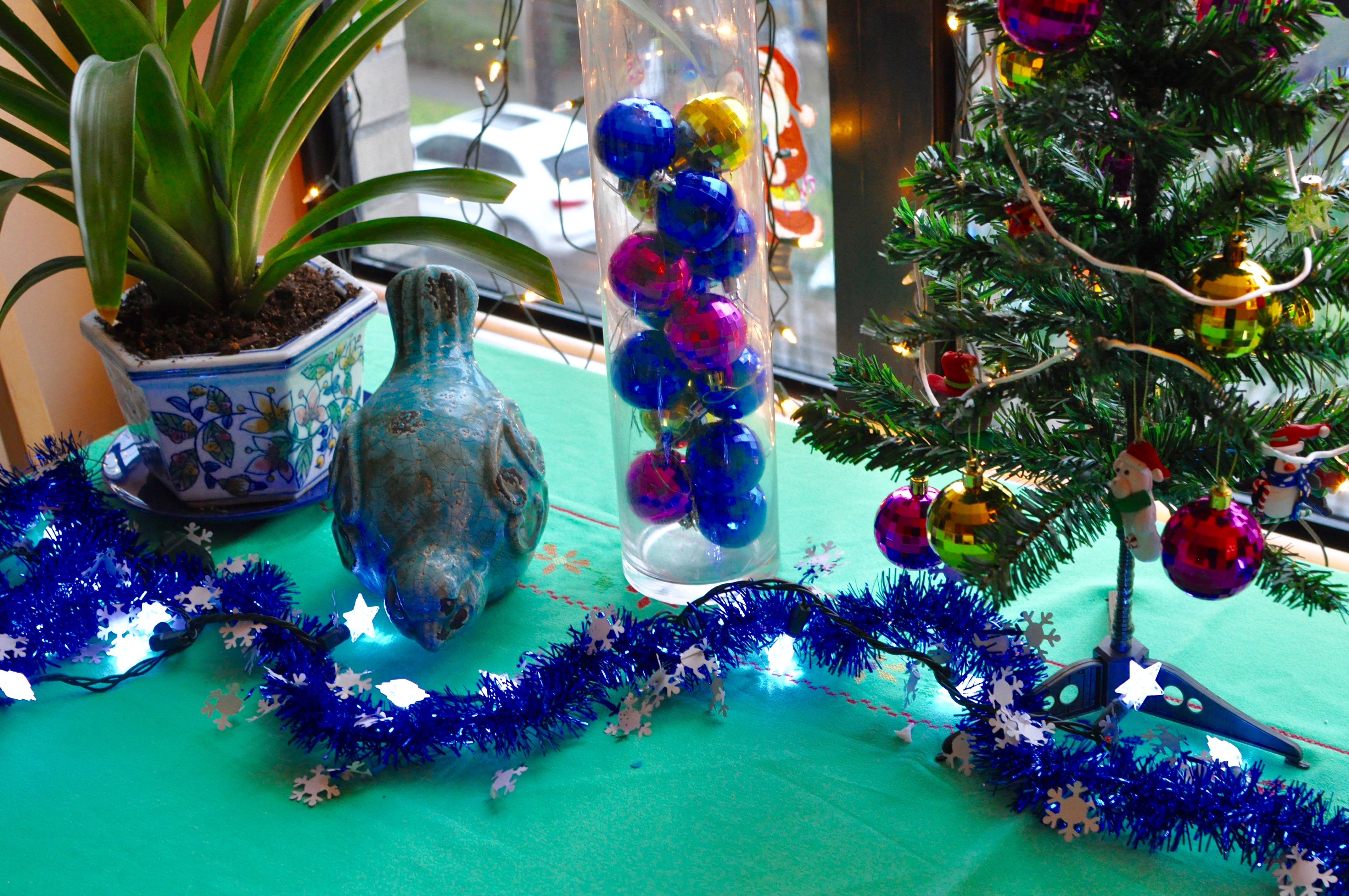 Close up of bird decorations and Christmas tree on a kitchen table with lights.