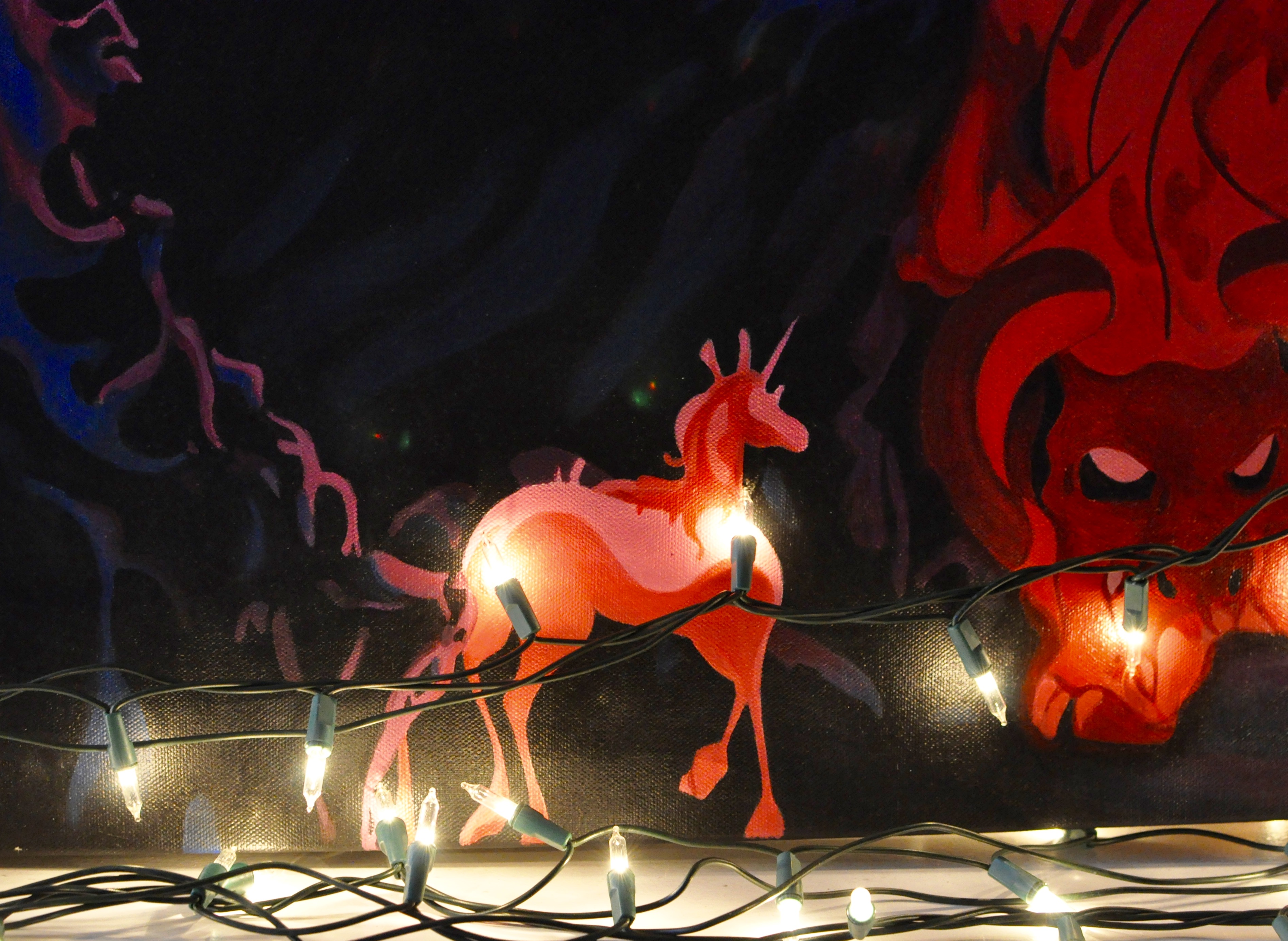 Close up of Christmas lights with the Last Unicorn painting in background.