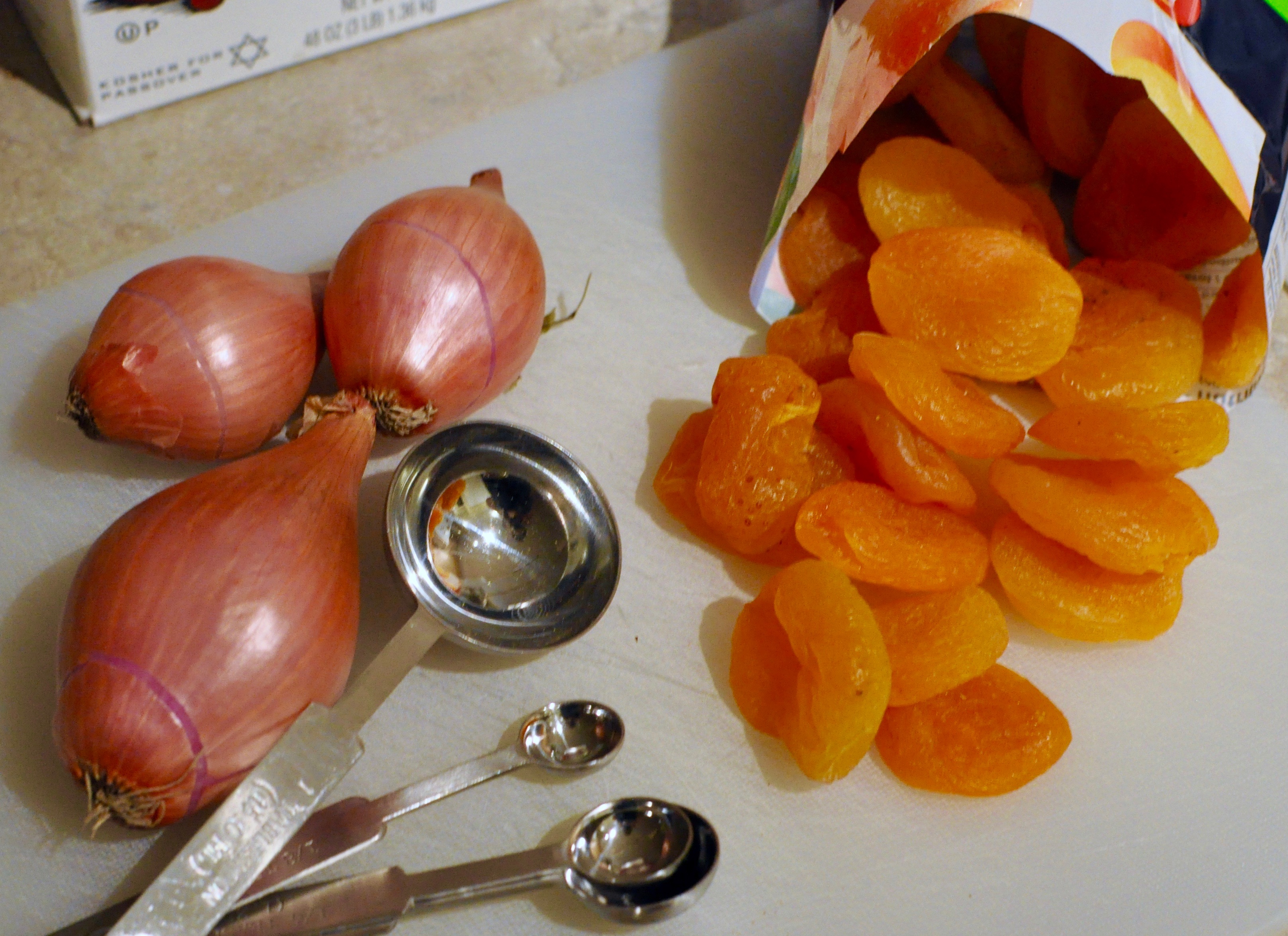 Apricots and shallots on a cutting board.