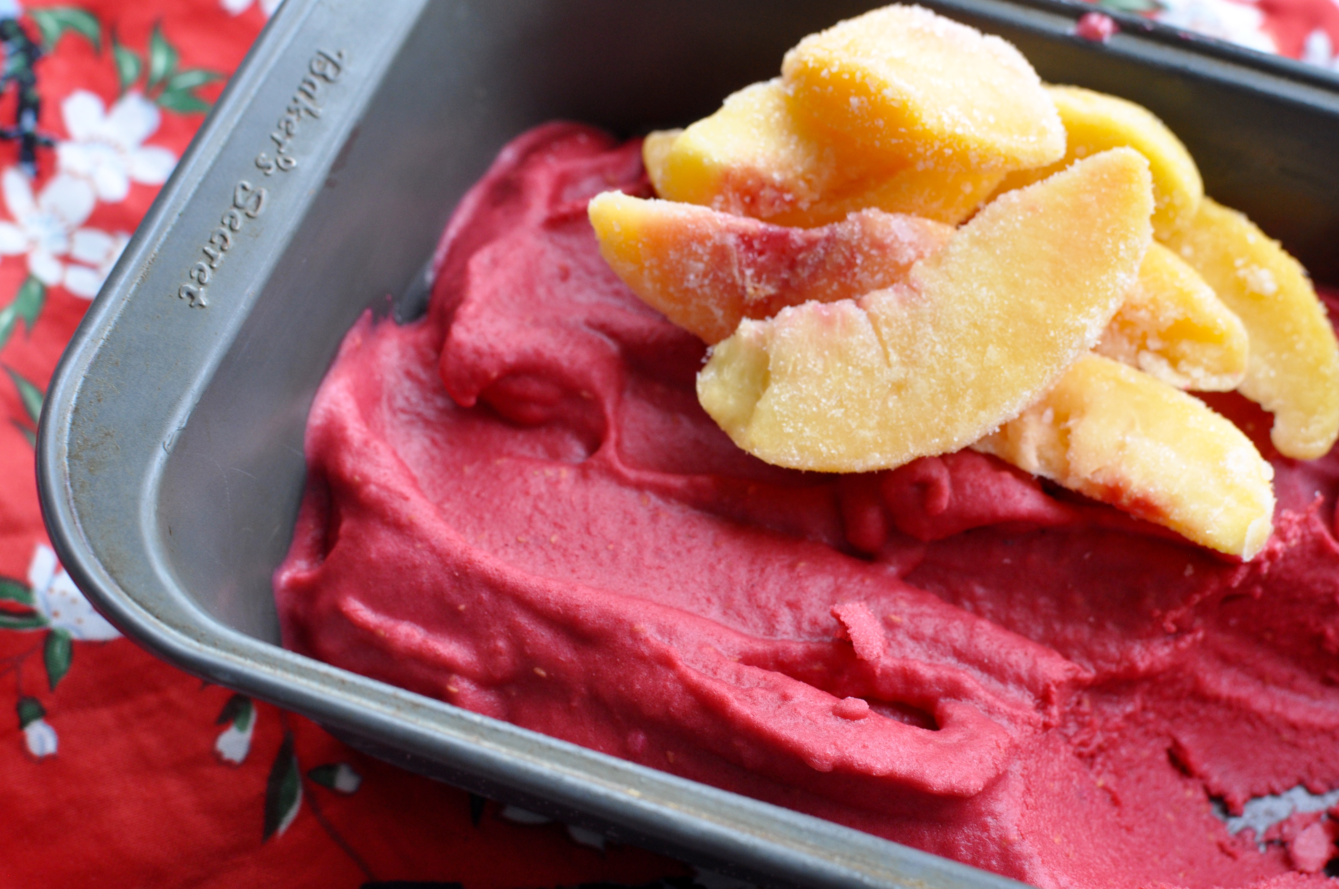 Loaf pan full of bright magenta frozen Greek  yogurt on a red table cloth.