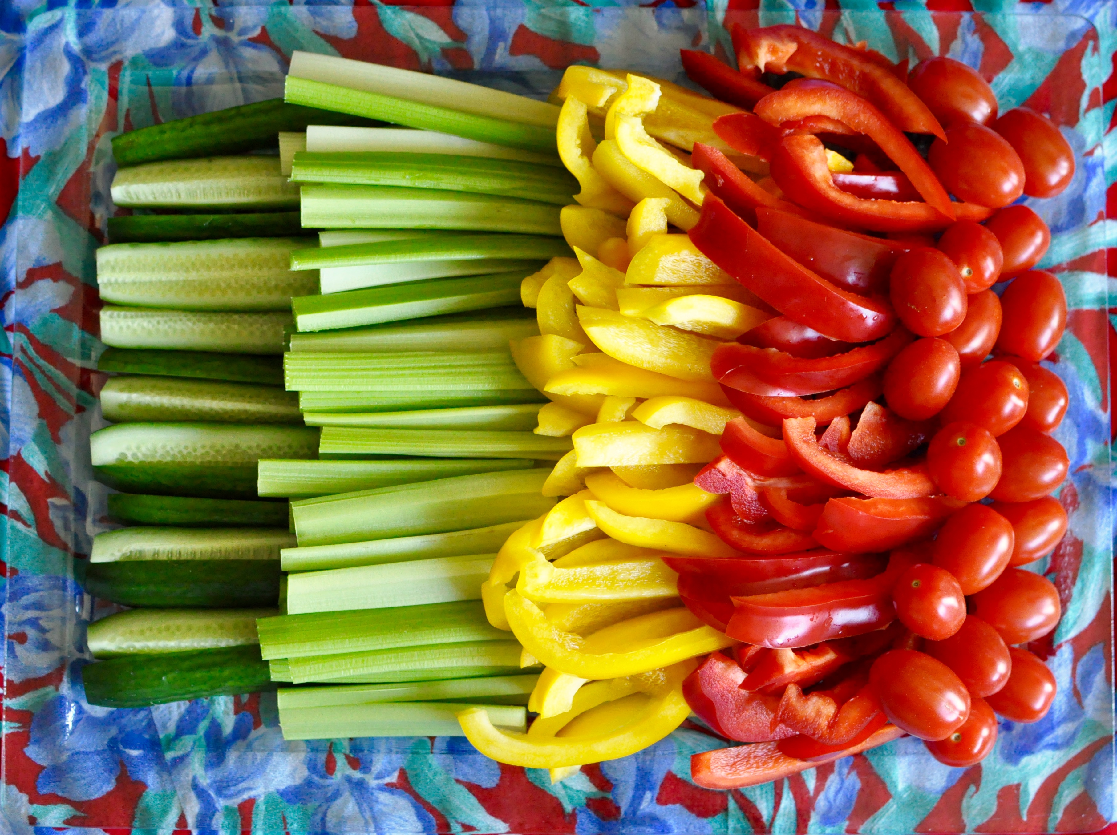 Tray of cut up peppers, celery, cucumber, and grape tomatoes.