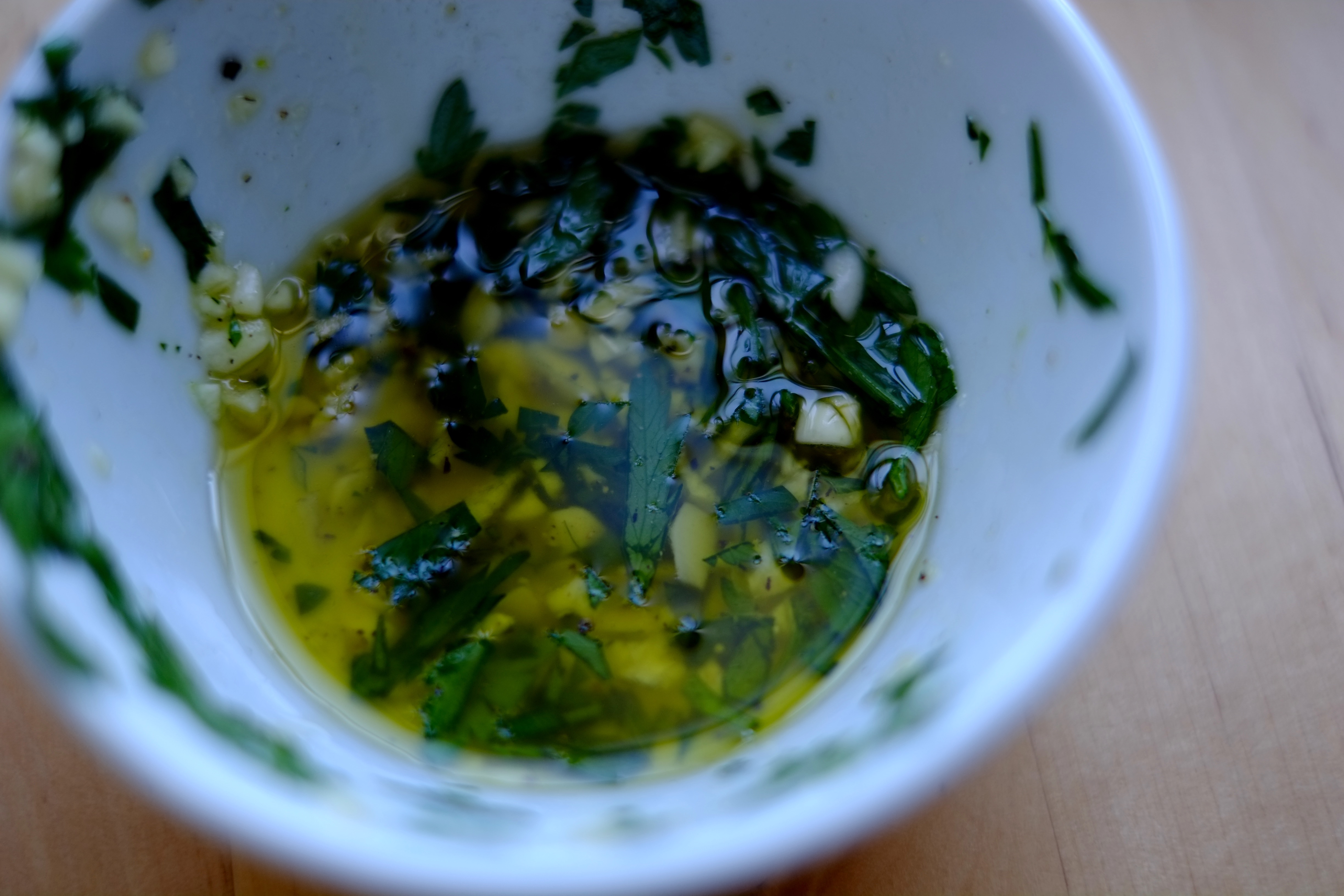 Close-up photo of olive oil with parsley and garlic.